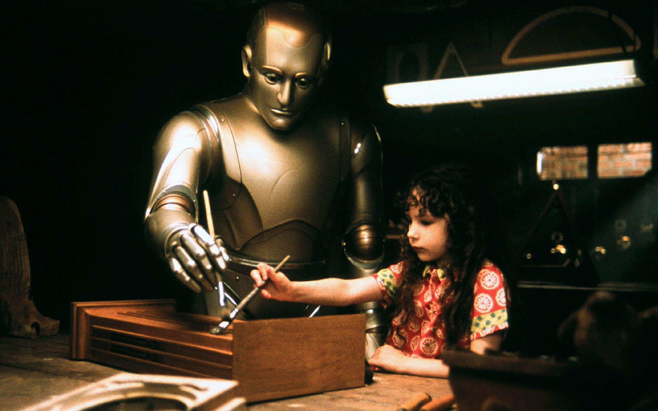 Robin Williams as Andrew the android in the movie Bicentennial Man uses a paintbrush along with a child with long brown hair who also holds a paintbrush.